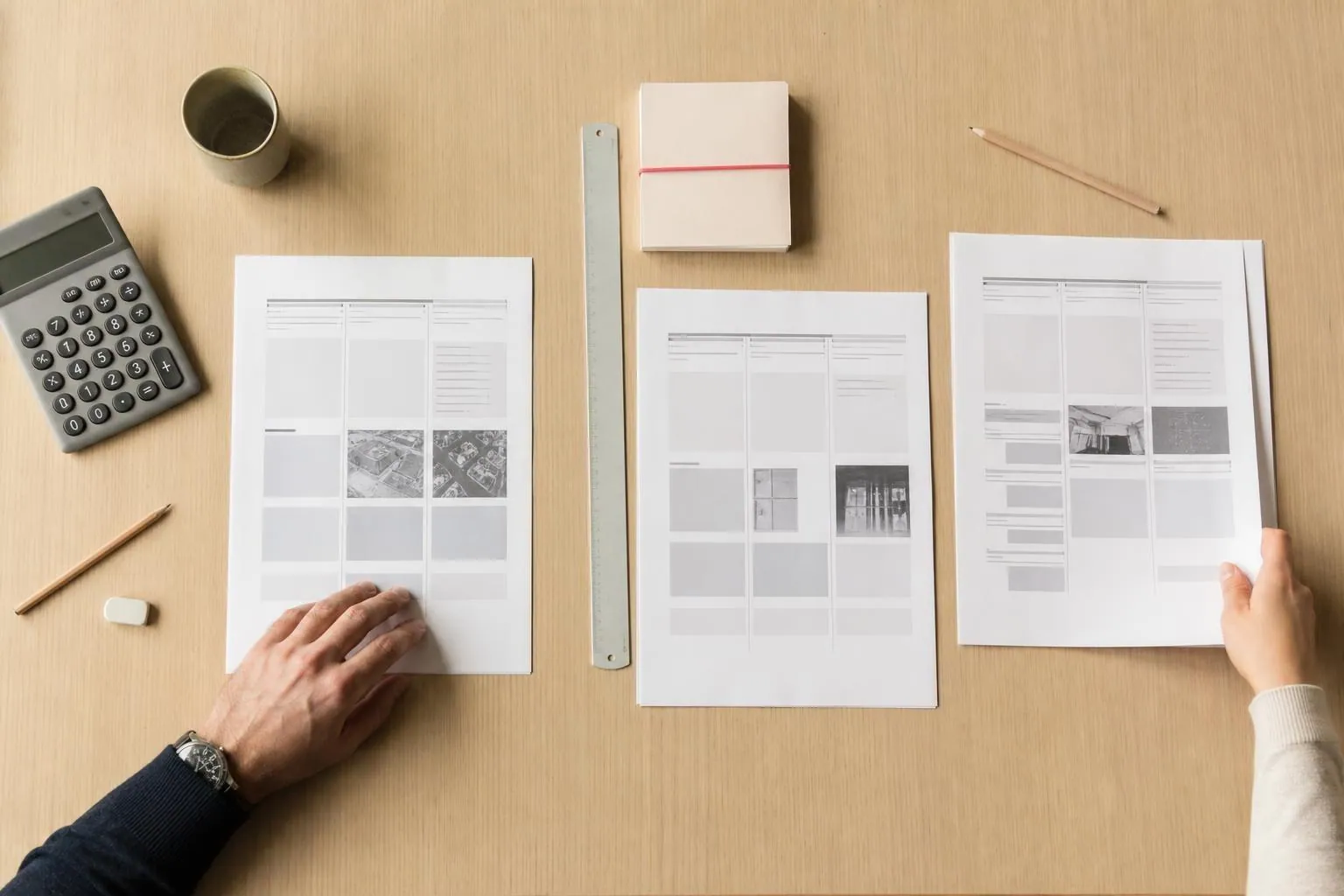 Vue en plongée de trois jeux de documents comparés côte à côte sur une table de réunion en bois clair